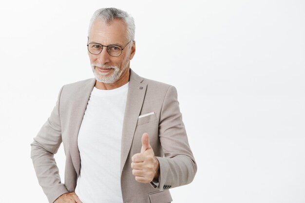 Handsome successful senior businessman showing thumbs-up in approval