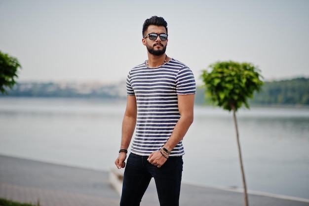 Красивый высокий арабский бородатый мужчина модель в раздетой рубашке позирует на улице Модный арабский парень в солнцезащитных очках
