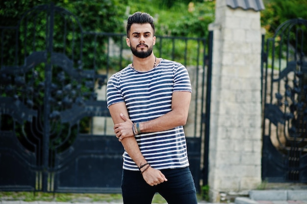 Handsome tall arabian beard man model at stripped shirt posed outdoor Fashionable arab guy