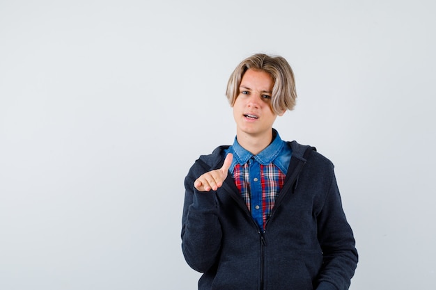 Handsome teen boy in shirt, hoodie showing stop gesture and looking cool , front view.