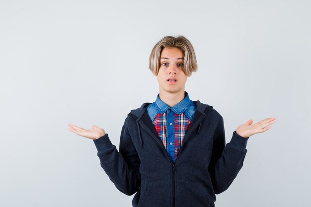 Free photo handsome teen boy showing helpless gesture in shirt, hoodie and looking puzzled , front view.