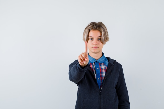 Handsome teen boy showing hold on a minute gesture in shirt, hoodie and looking confident , front view.