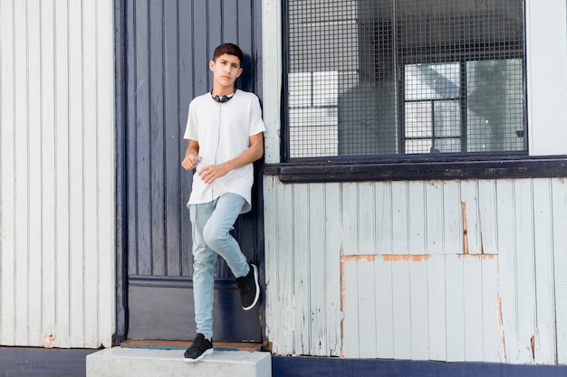 Handsome teenage boy leaning on corrugated iron siding looking at camera