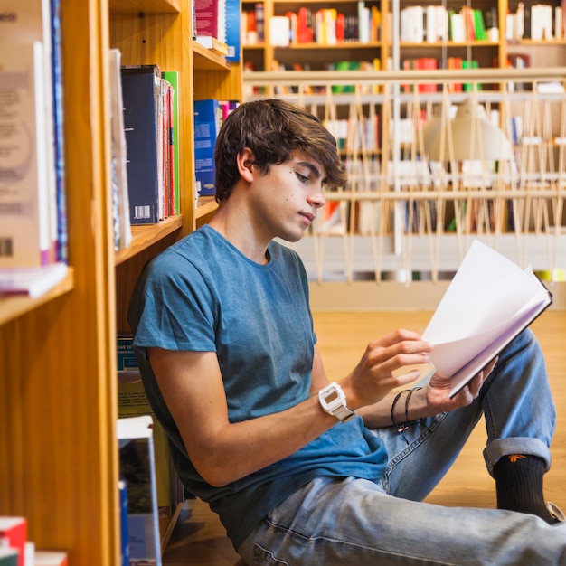 Handsome teenager turning pages of book