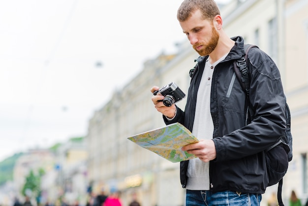 Free photo handsome tourist with camera and map