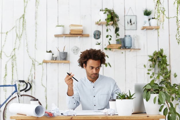 Free photo handsome unshaven young dark-skinned engineer having confused look