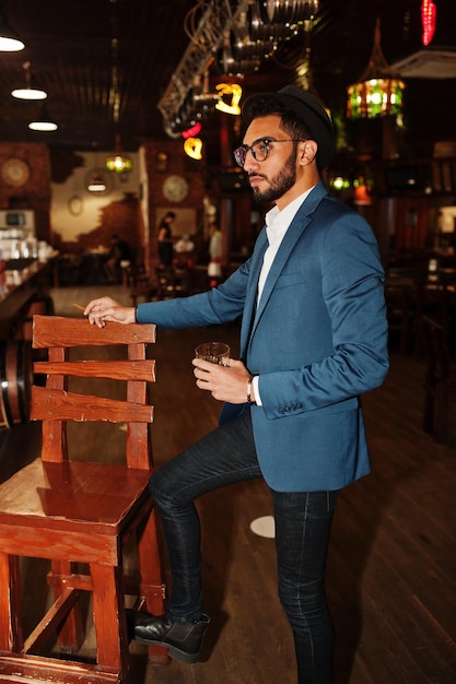 Free photo handsome welldressed arabian man with glass of whiskey and cigar posed at pub