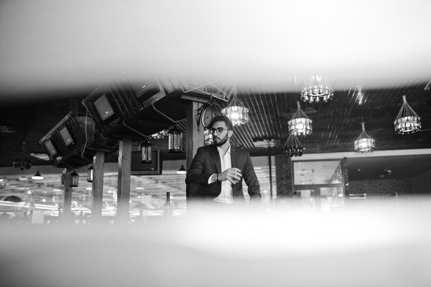 Handsome welldressed arabian man with glass of whiskey and cigar posed at pub