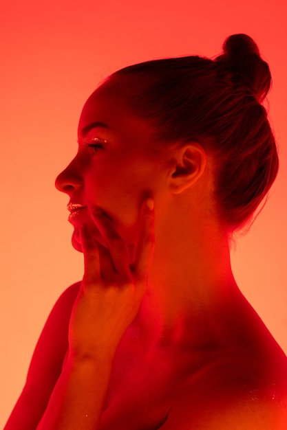 Handsome woman's portrait isolated on red-orange studio background in neon light, monochrome. Beautiful female model. Concept of human emotions, facial expression, sales, ad, fashion and beauty.