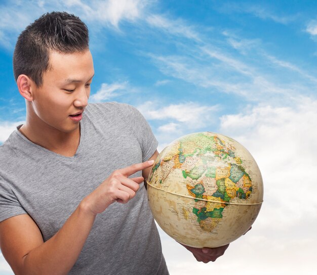 handsome young asian man indicating some location on a globe