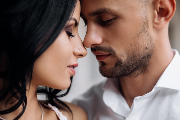 Handsome young bald headed man hugs with passion young brunette in pink evening dress