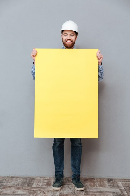 Handsome young bearded builder holding blank board