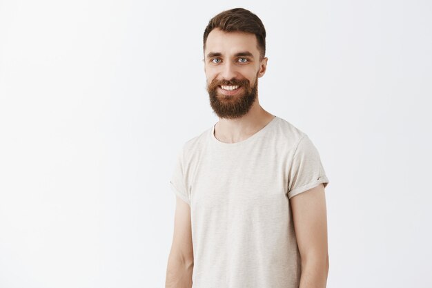 Handsome young bearded man posing against the white wall