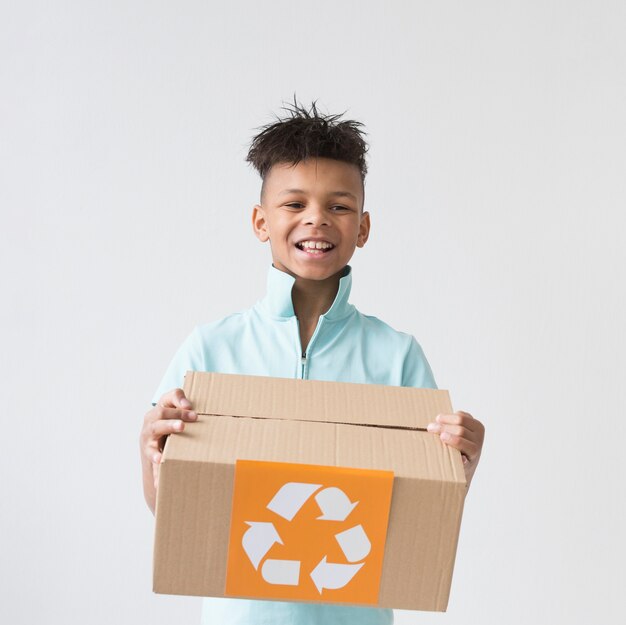 Handsome young boy holding recycling box