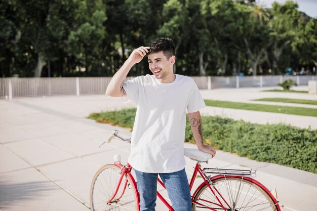 Handsome young boy standing with his bicycle in park