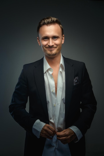 Handsome young business man in a suit over grey background.