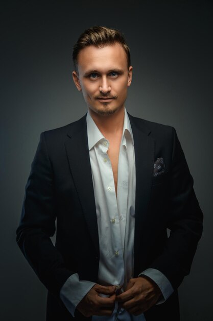 Handsome young business man in a suit over grey background.