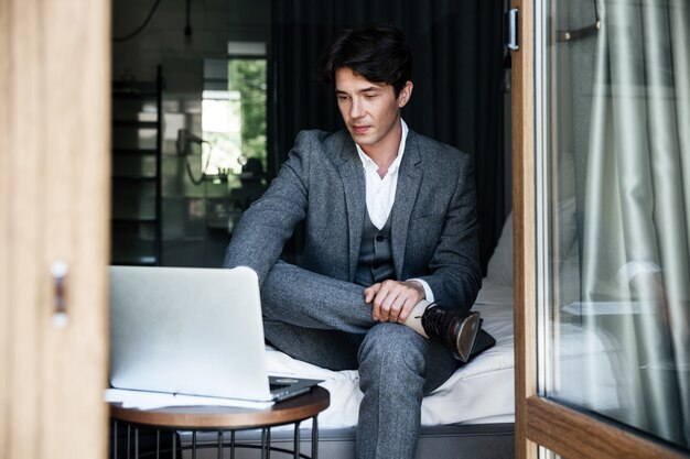 Handsome young businessman in suit working on laptop