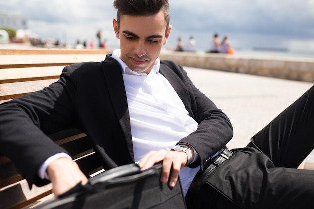 Handsome young businessman taking papers from bag