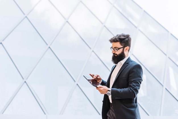 Free photo handsome young businessman using digital tablet at outdoors