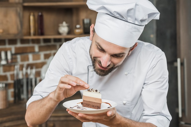 Foto gratuita giovane cuoco unico bello che decora dessert delizioso