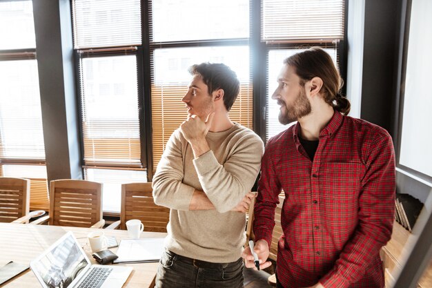 Handsome young colleagues in office working with desk