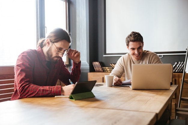 Handsome young colleagues working in office