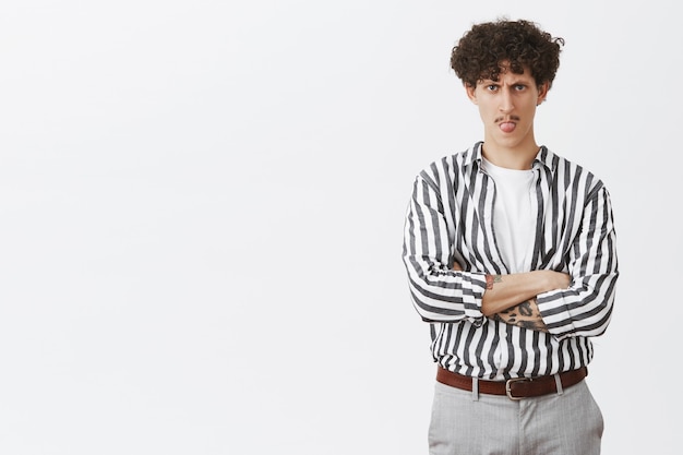 Free photo handsome young curly-haired guy showing tongue