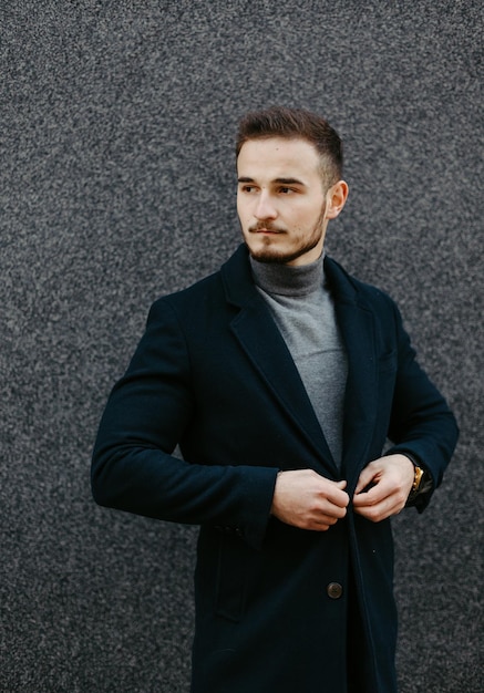 Free photo handsome young fashion model posing on city streets.outdoor fashion portrait, stylish man in elegant coat.