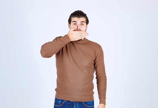 Free photo handsome young guy model covering mouth with hand.