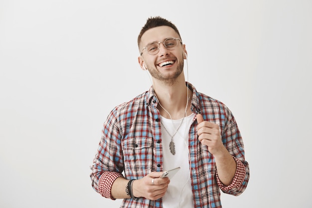 Handsome young guy with glasses posing with his phone and earphones