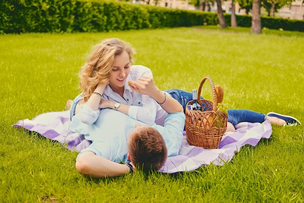 Handsome young male and blond female on a picnic in a summer park.