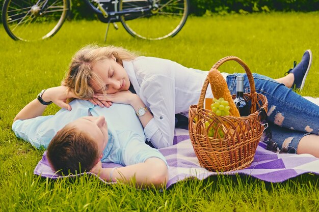 Handsome young male and blond female on a picnic in a summer park.