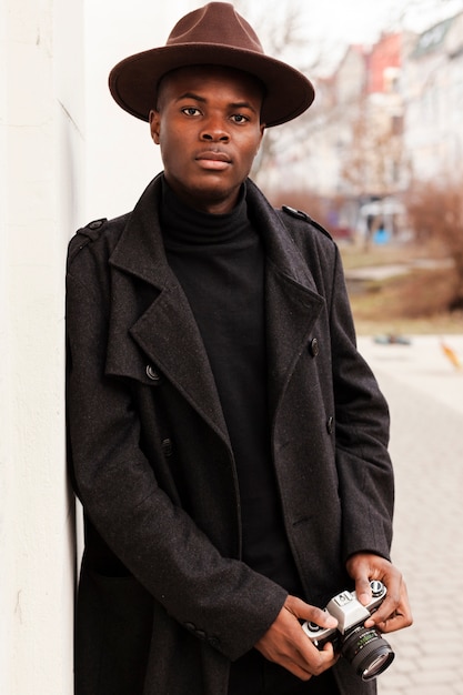 Foto gratuita giovane maschio bello che propone con il cappello moderno