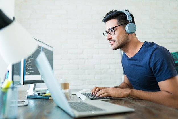 Handsome young male software developer programming codes while working from home