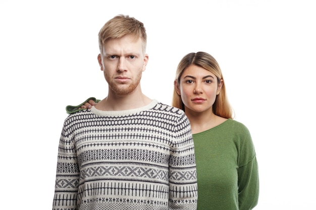 handsome young male with beard staring with serious look expressing readiness and confidence, his supportive girlfriend standing behind him with her hand on his shoulder