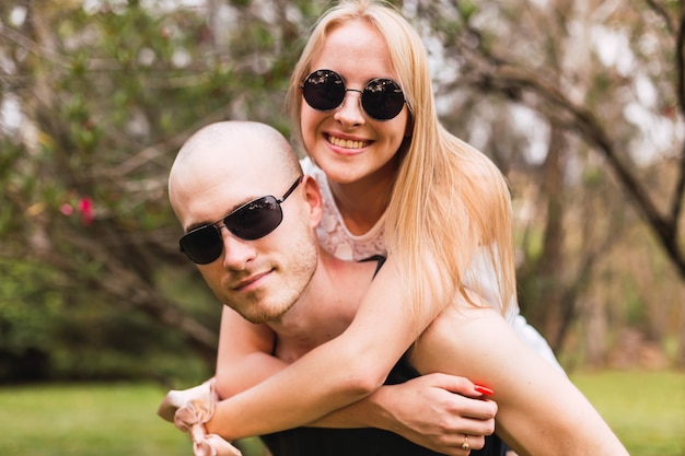 A handsome young man carrying his girlfriend on his back while she smiles - a day to share moments  a young man bringing piggyback to a young woman