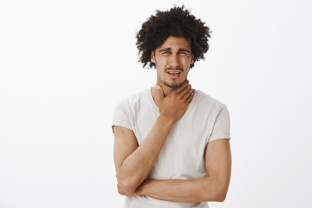 Handsome young man complaining on sore throat, got sick