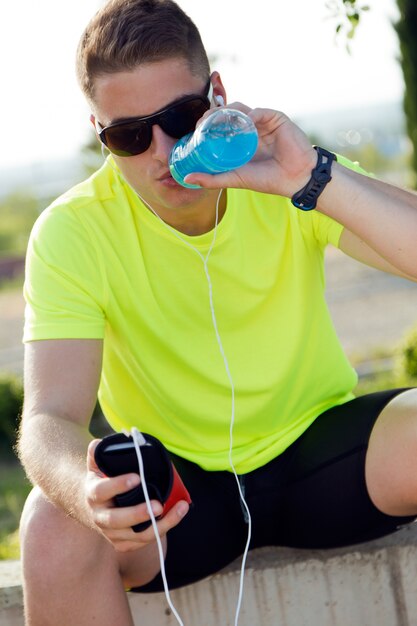 Handsome young man drinking after running.