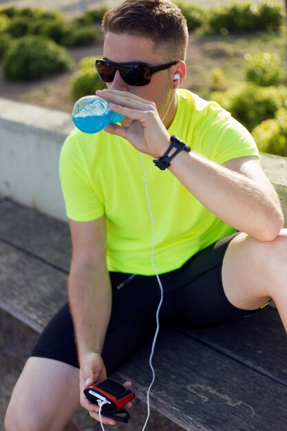 Handsome young man drinking after running.