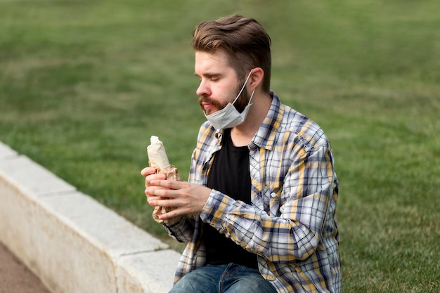 Free photo handsome young man eating a kebab