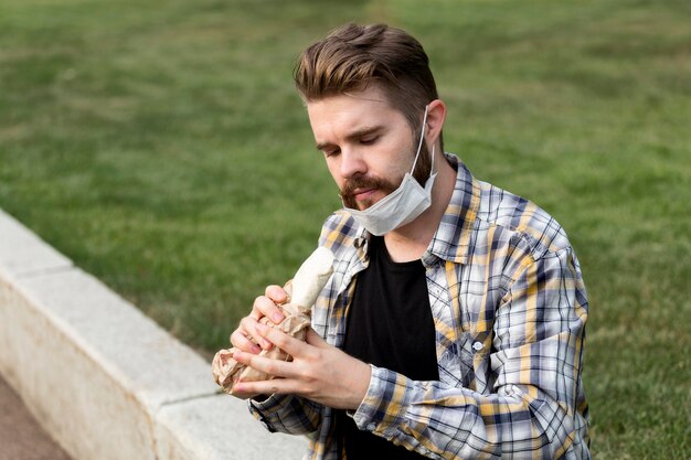 Free photo handsome young man eating a kebab