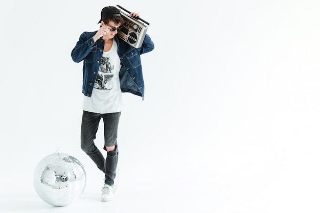 Free photo handsome young man holding boombox near disco ball