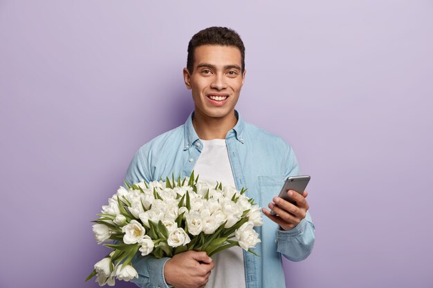 白いチューリップの花束を保持しているハンサムな若い男