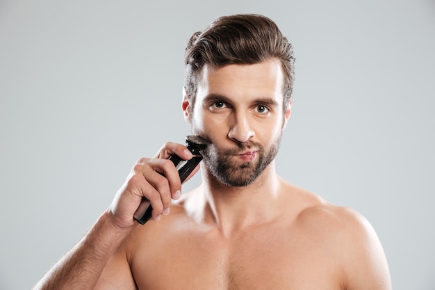 Handsome young man holding electric razor