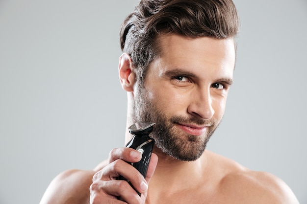 Handsome young man holding electric razor