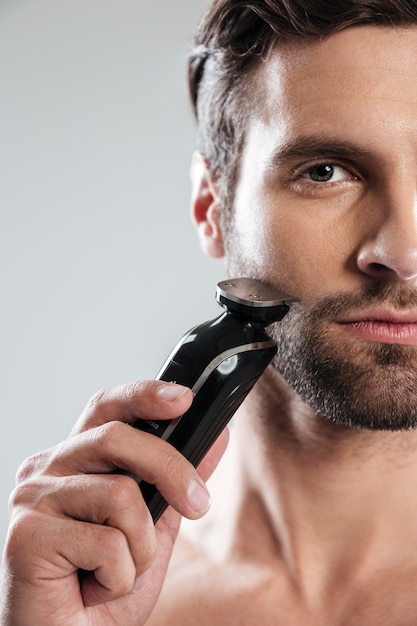 Handsome young man holding electric razor