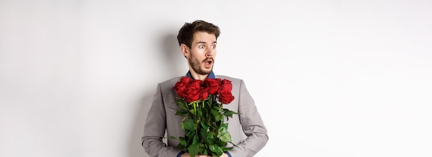 無料写真 赤いバラを保持しているスーツを着たハンサムな若い男