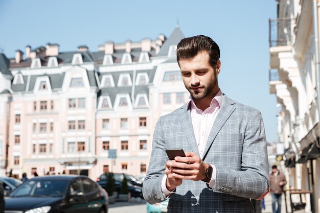 Handsome young man in jacket looking at mobile phone