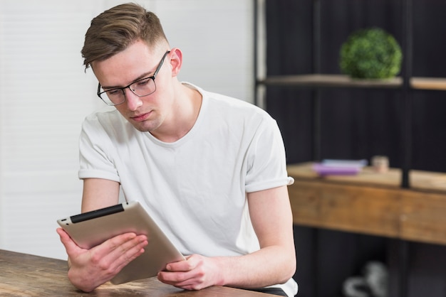 Free photo handsome young man looking at digital tablet